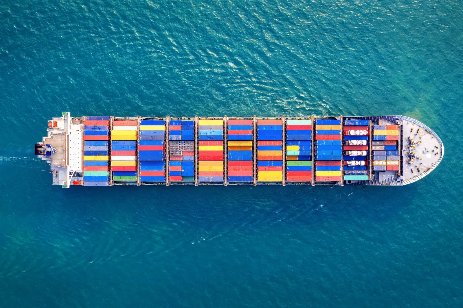 Aerial view of a fully-loaded container ship crossing open blue water.